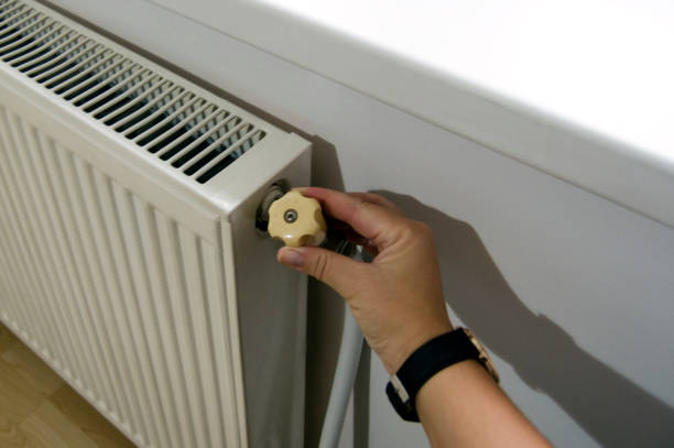 istock Woman's hand turns the battery heating knob. 2176750495