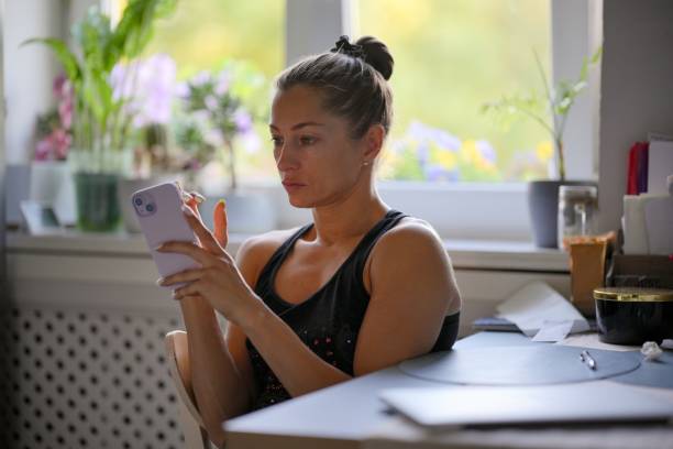 A Sad Young Woman is Engaged with Her Smartphone While in a Stylish Modern Kitchen Setting