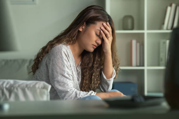 young asian woman sitting in a bedroom, head in hands, feeling sad tired and worried suffering depression in mental health. in concept of depression anxiety and insomnia - うつ病 ストックフォトと画像