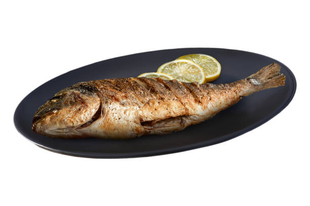 Showcase the fresh, succulent texture of grilled sea bream. Ideal for menus, this close-up shot emphasizes the crispy skin of fish on a plate.