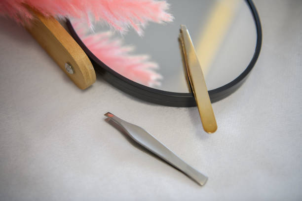 two tweezers next to a small mirror. aesthetics