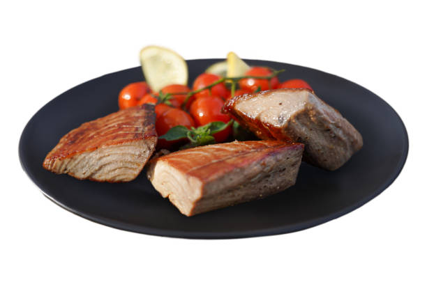 Highlight the fresh, delicate texture of a blue fish fillet with cherry tomatoes on a plate. Perfect for seafood menus, this close-up shot brings out its natural appeal.