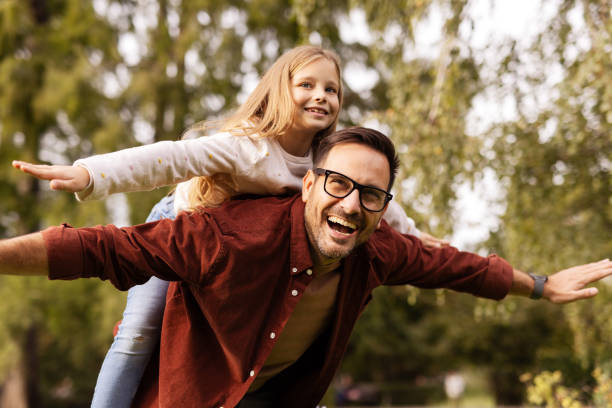 istock Smiling father piggybacking daughter with arms outstretched 2176772681
