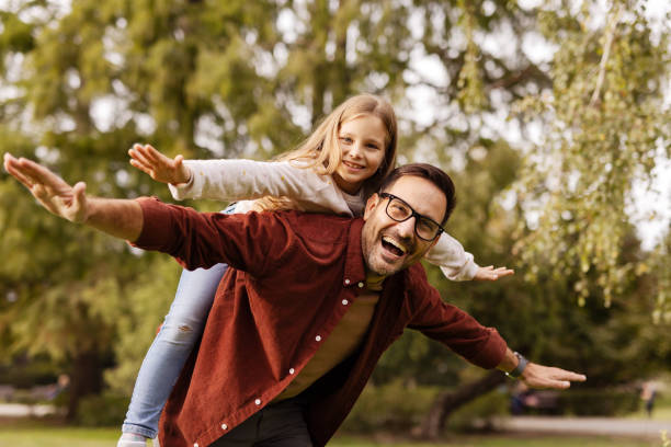 istock Smiling father piggybacking daughter with arms outstretched 2176772861