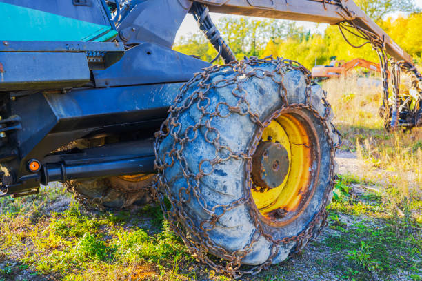 Close-up view of forestry machine's large wheel wrapped in rusty chains for enhanced traction on rough terrain. Sweden.