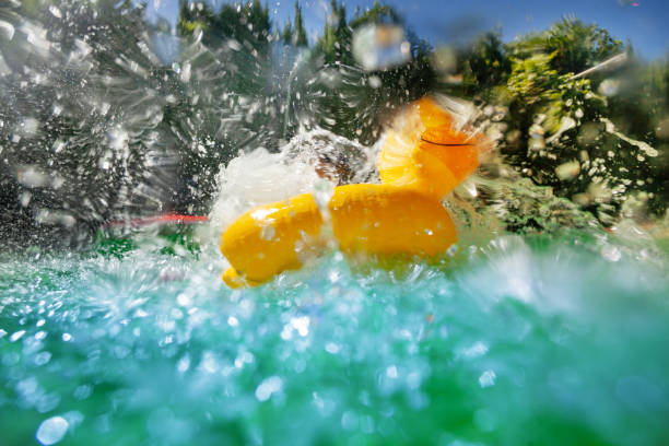 An inflatable yellow rubber duck splashing in the vibrant turquoise pool, with water droplets frozen in motion and a sunlit garden in the background