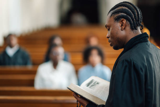 istock Young priest reading holy book during church service 2176799522
