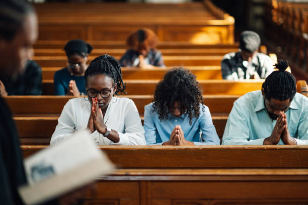 istock Congregation praying in church with priest holding bible 2176799535