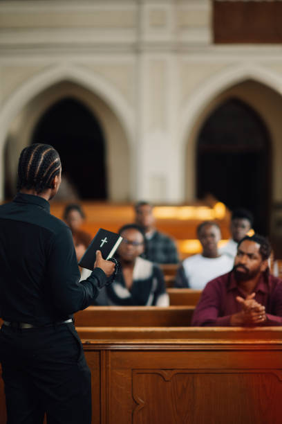 istock Pastor preaching and holding bible in church from behind 2176799586
