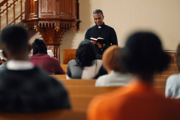 istock Young priest reading from the bible to his congregation 2176799588