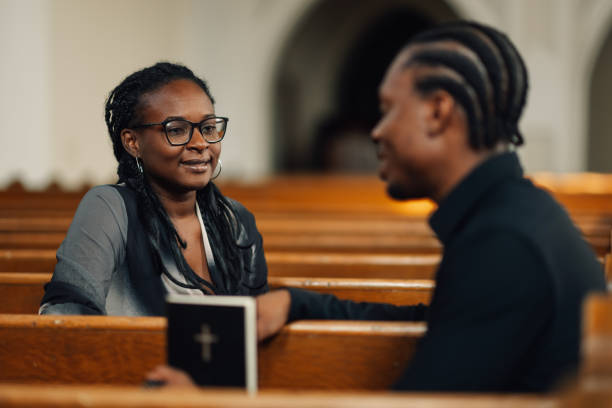 istock Young couple holding hands and talking in church pew 2176799621