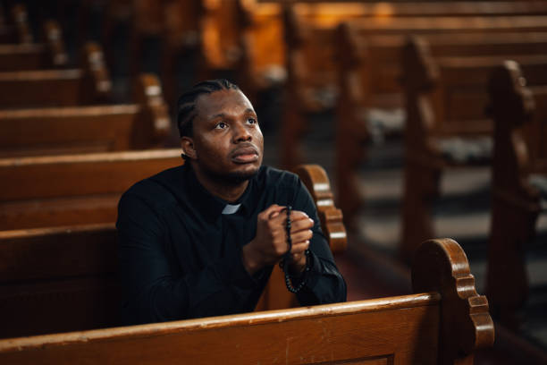istock Priest praying in church holding rosary beads 2176799634