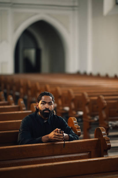 istock Priest praying with rosary beads in church pew 2176799656