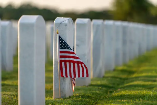 Grabsteine für Militärbegräbnisse. Sarasota National Cemetery mit Reihen weißer Grabsteine und USA-Flaggen auf grünem Gras. Konzept des Memorial Day Grabsteine für Militärbegräbnisse. Sarasota National Cemetery mit Reihen weißer Grabsteine und USA-Flaggen auf grünem Gras. Konzept des Memorial Day