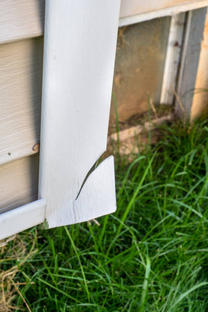 istock Broken vinyl siding on corner of house. 2176800985