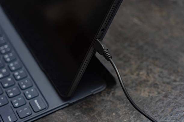istock Digital tablet charges on the concrete table with a cable. Concept for charging the battery of gadgets. 2176813776