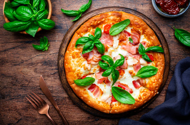 istock Small hot pizza with pancetta, mozzarella, tomato and basil on wooden background, top view 2176814535
