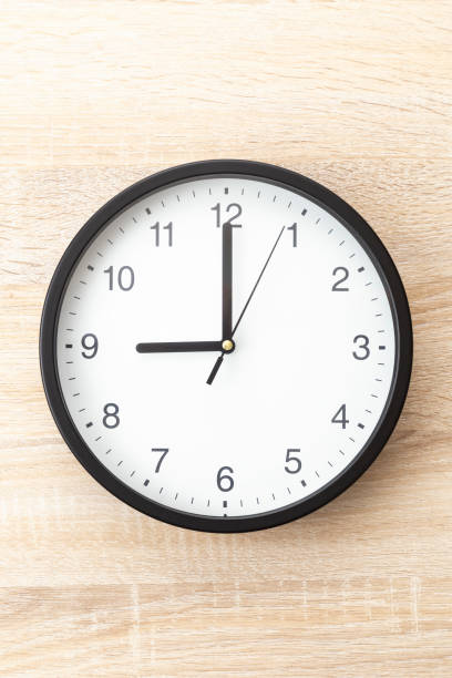 istock Wall clock on a wood grain background. 2176822753
