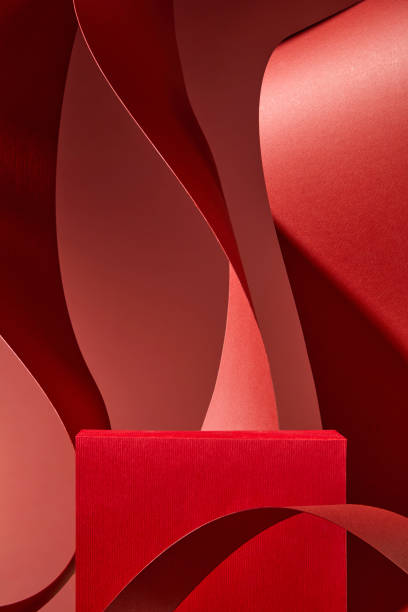 istock The image is traditional minimalist; a red rectangular podium is placed in the center to display the product. The red backdrop is surrounded by an abstract backdrop of curved red paper strips. 2176831142