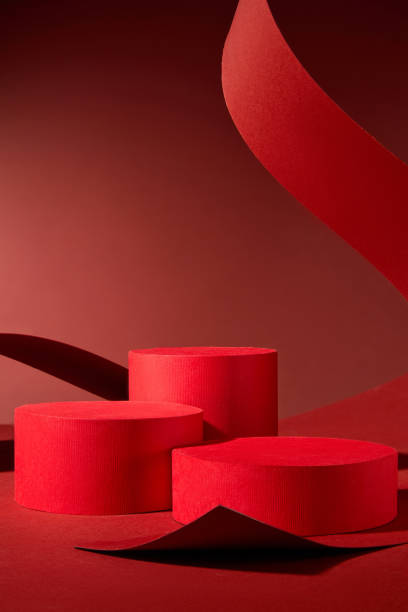 istock This elegant design features three red cylindrical podiums on a red background, ideal for presenting items or branding. A colorful show is created by curling and arching a large red paper over the podiums. 2176831213