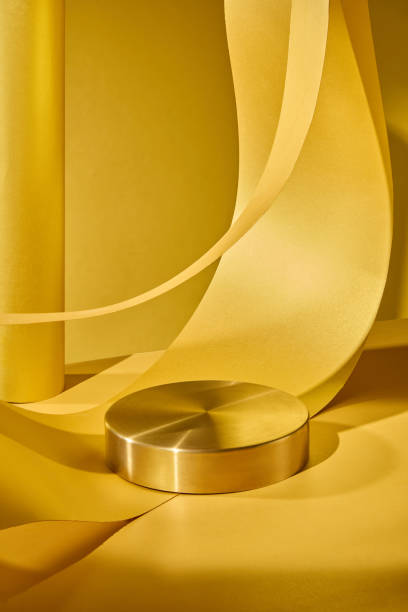 istock A isolated yellow cylindrical podium is positioned against a yellow backdrop, and curved yellow paper strip is placed behind the pedestal to create exquisite display appropriate for product placement. 2176831520