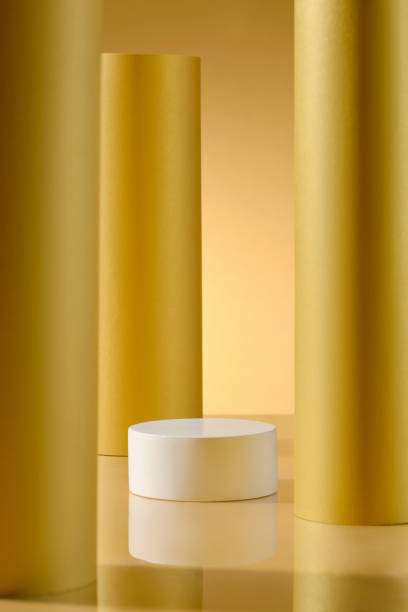 istock This image presents a pristine white cylindrical platform for product display against a backdrop of three yellow cylinders. The subtle reflections on the floor add a sense of depth to the image. 2176831806