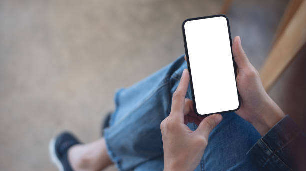 istock Cell phone white blank screen mockup, woman's hand holding mobile phone with blank screen and a cup of coffee in coffee shop, overhead shot, social media marketing design 2176842448