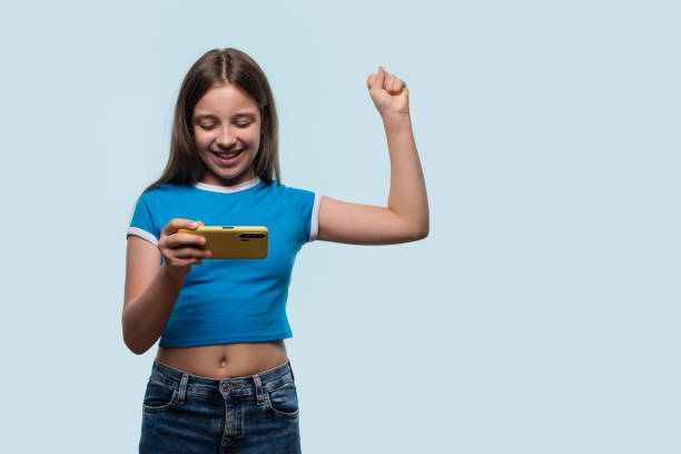 istock Girl happily cheering while using smartphone, celebrating success 2176866156