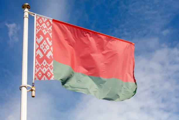 A flag with a red and green background is flying in the sky. The flag is on a pole and is waving in the wind