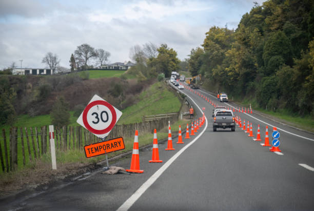 istock Orange traffic cones on the road. Unrecognizable workers directing the traffic. Roadwork in Hawkes Bay. 2176871106