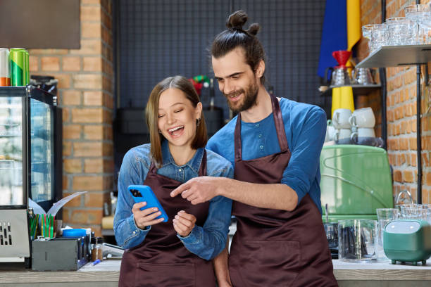 istock Young man and woman restaurant coffee shop workers using smartphone together 2176871189