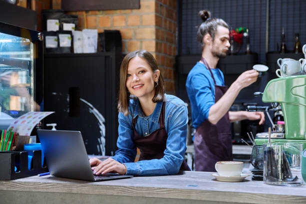 istock Young woman coffee shop worker in apron using laptop computer at bar counter 2176871275