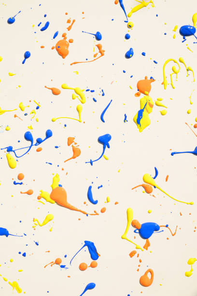 istock Vibrant abstract composition featuring blue, yellow, and orange paint splattered across a cream background. 2176878962