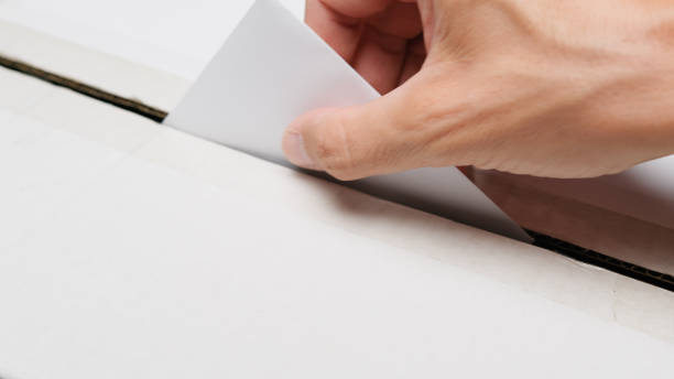istock Hand inserts ballot paper into the box 2176879452