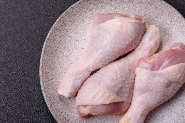 istock Raw chicken legs with salt, spices and herbs on a dark concrete background 2176882989