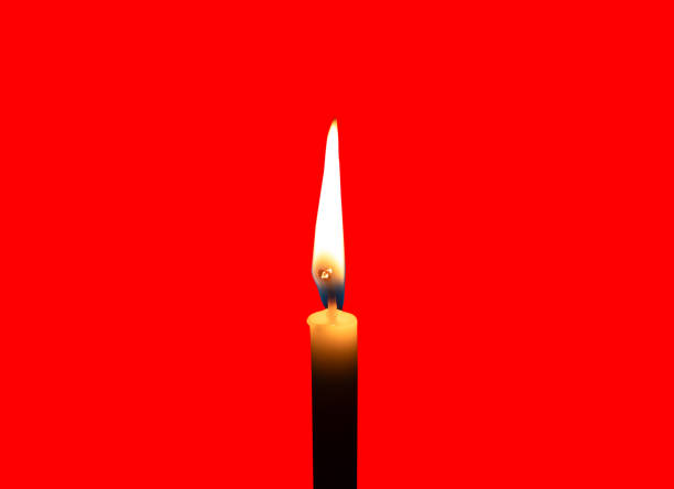 A single burning candle flame or light glowing on a small white candle is isolated on red background with clipping path.