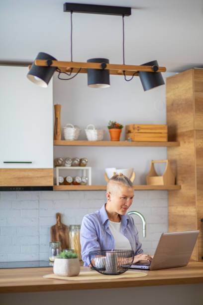istock Woman using laptop in the morning in the kitchen 2176889347