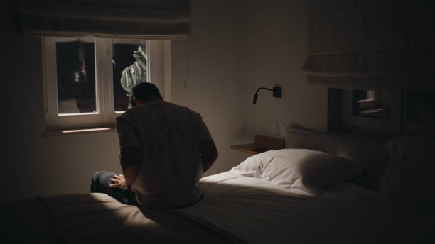istock Troubled man sitting night bedroom home by window feeling melancholic back view 2176891072