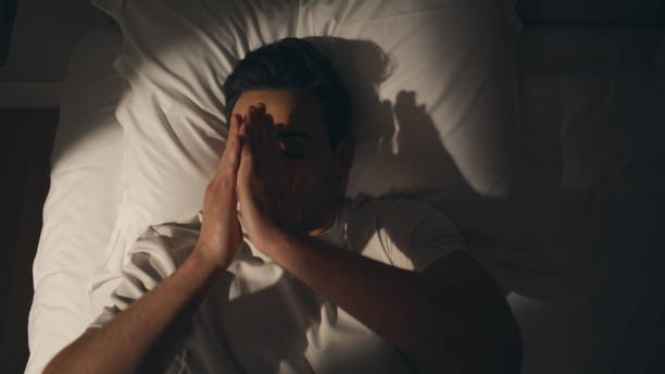 istock Man feeling stress bed at night closeup top view. Unhappy guy lying pillow 2176892005