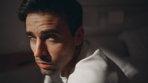 istock Pensive guy sitting bedroom looking window at moonlight closeup. Thoughtful man 2176894622