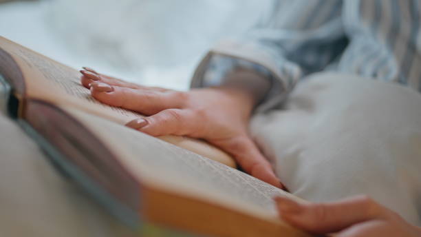 istock Unrecognizable woman reading book lying under cozy blanket closeup. Girl reader 2176895472