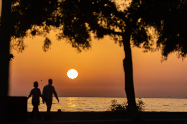 Sun is setting over by Marmara sea with silhouette of people.