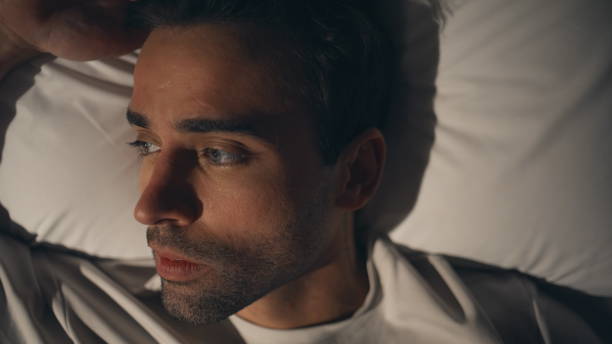 Sad young man with pillow at home