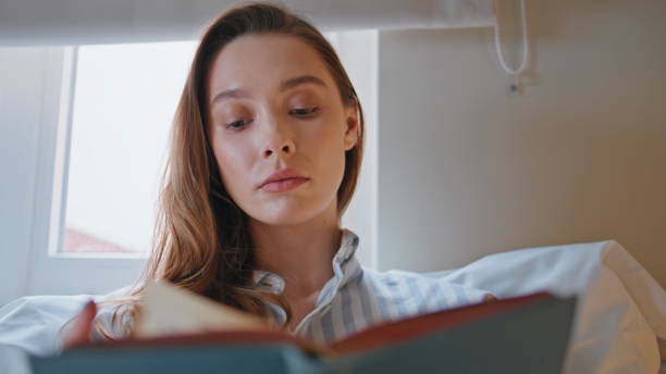 istock Focused woman studying book with thoughtful expression in bedroom closeup. 2176904077