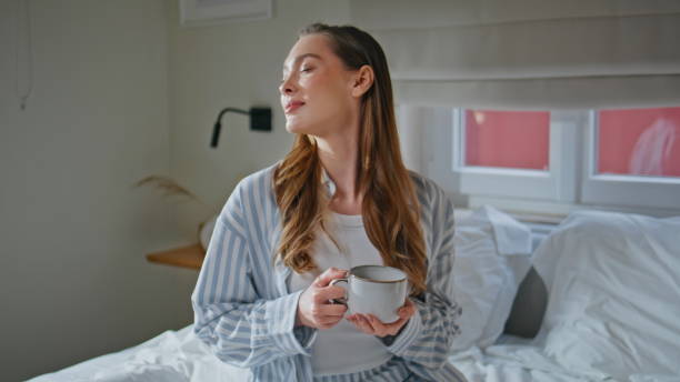 istock Relaxed lady holding cup beverage on comfortable bed at weekend morning closeup. 2176905079