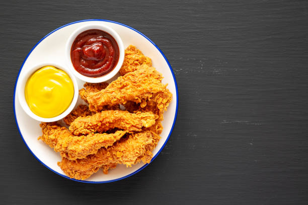 istock Homemade Chicken Strips with Mustard and BBQ on a Plate on a black background, top view. Flat lay, overhead, from above. Space for text. 2176913662
