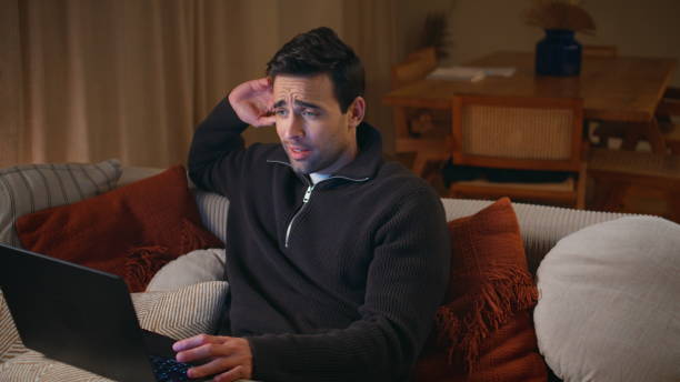 istock Man video chatting laptop sitting on couch radiating happiness. Guy conference 2176933329