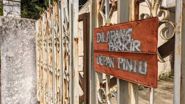 istock gate with a sign saying no parking here in Indonesian 2176937550