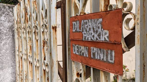 istock gate with a sign saying no parking here in Indonesian 2176937552