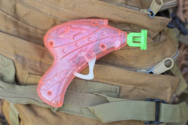 one pink plastic gun lies on brown fabric backpack on summer street
